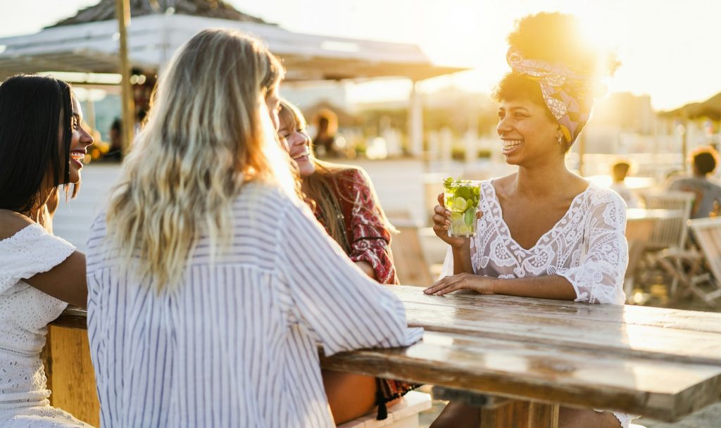 Happy girls having fun drinking cocktails at bar on the beach