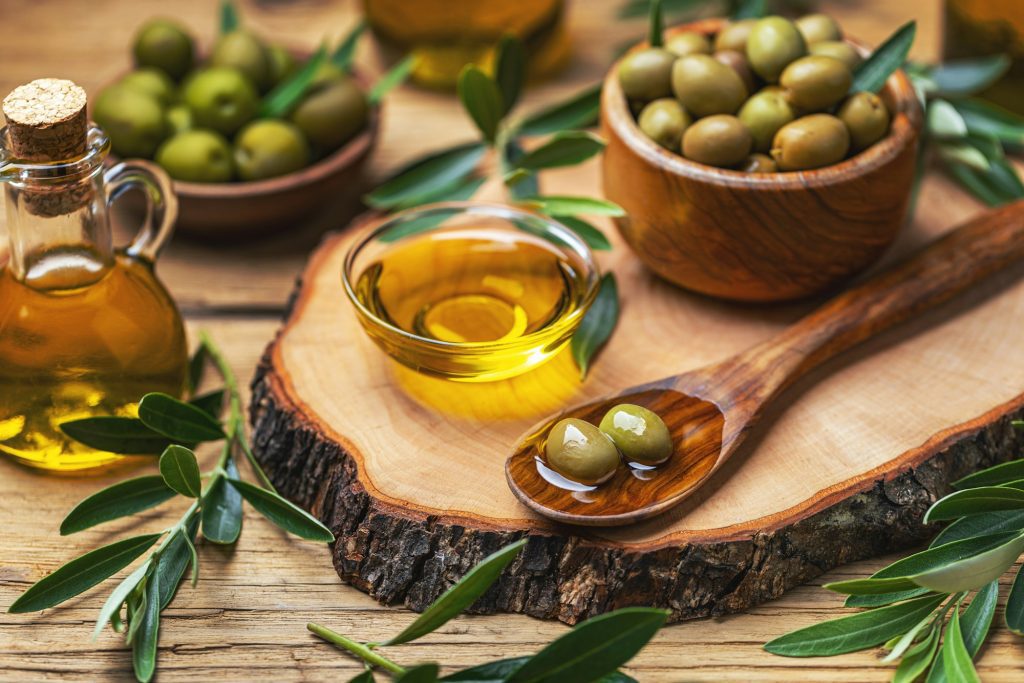 Organic olive oil in bowl with green olives