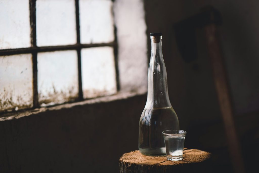 Strong alcohol drink in bottle with shot glass